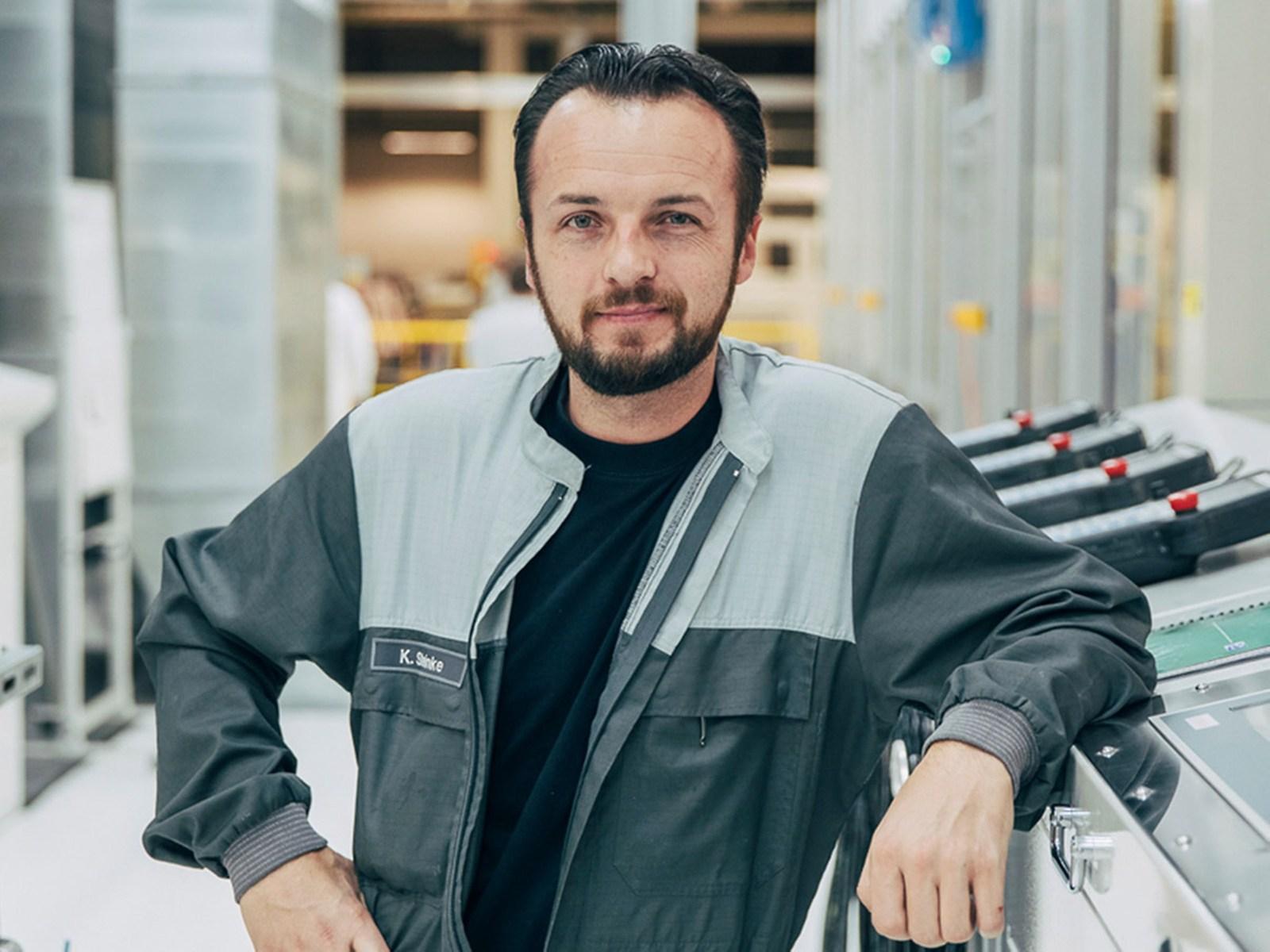 A man in work clothes looks into the camera